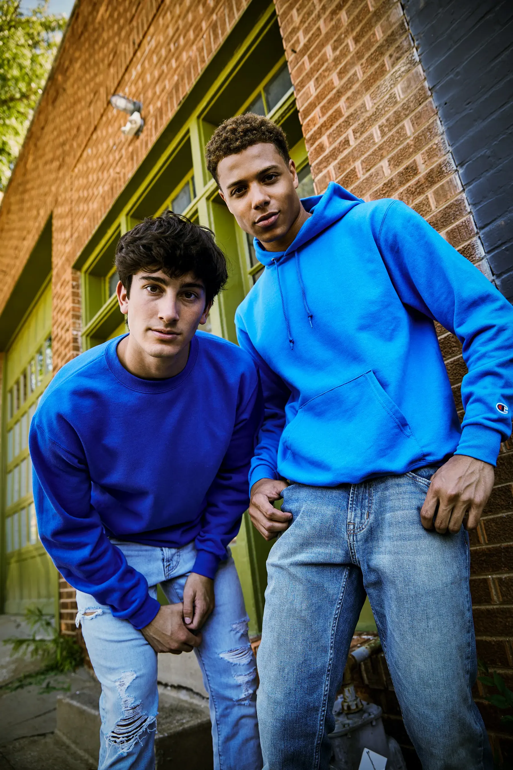 The same photograph before the work: both sweatshirts are plain bright blue, one royal and one cyan, with no team marks on either.