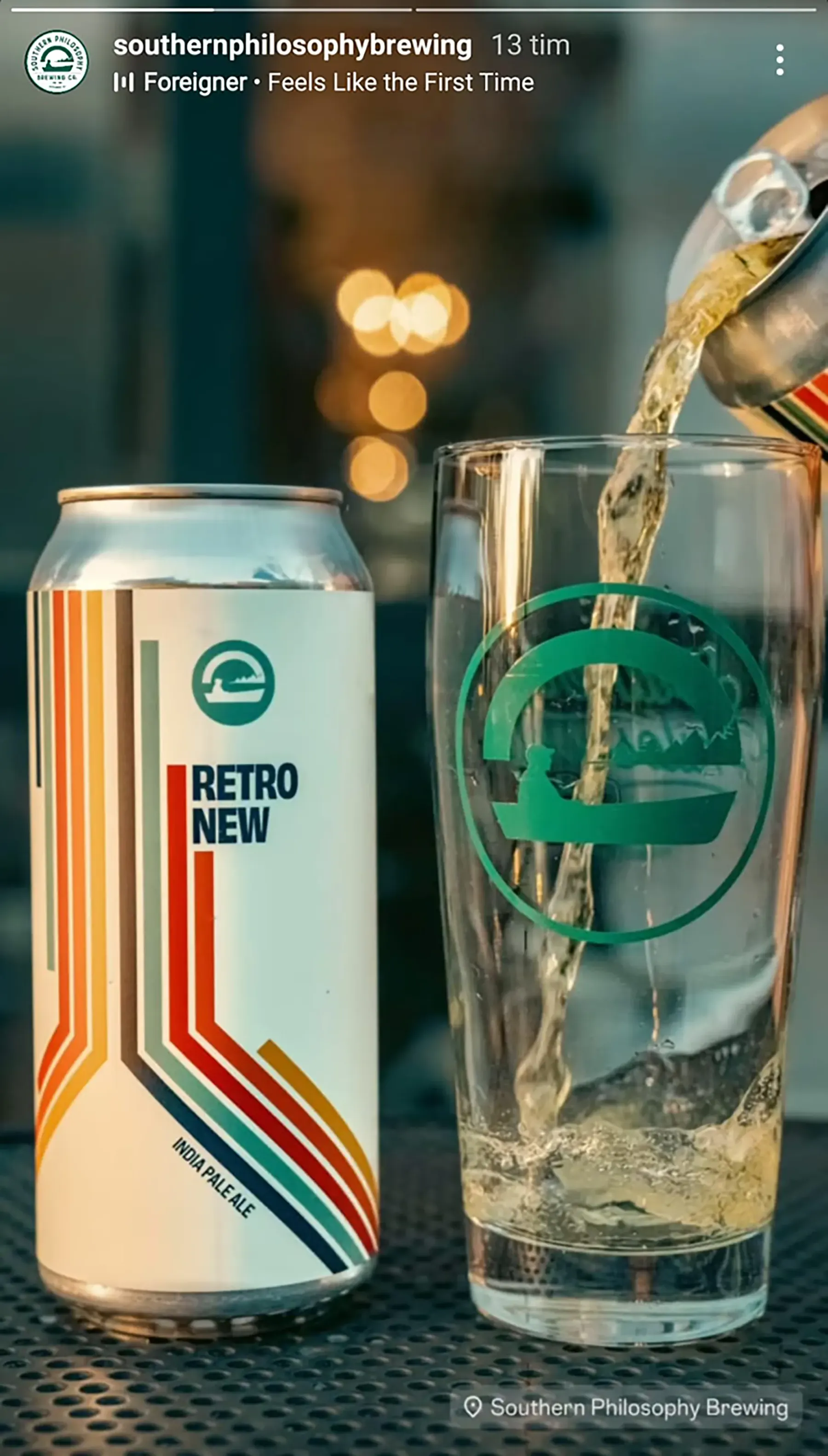 A social post from the brewery: a Retro New can standing on a bar grate beside a tall glass being filled, the brewery's canoe roundel etched on the glass and warm bar lights out of focus behind.