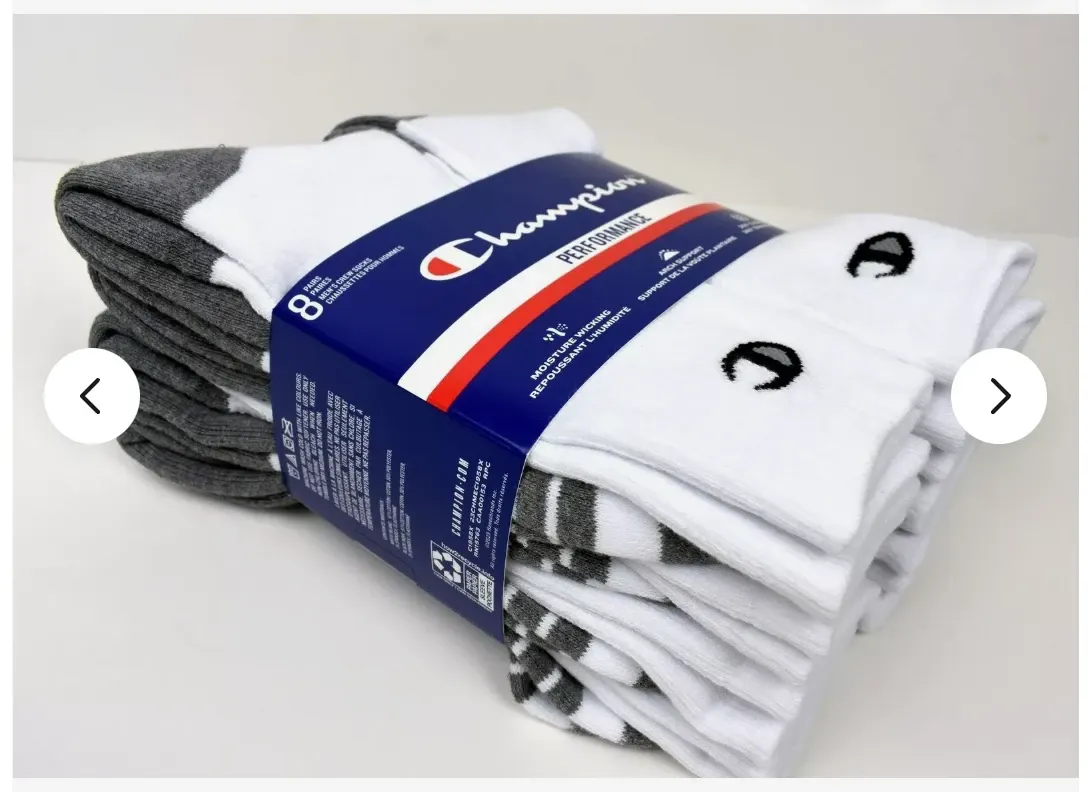 A banded eight-pack of Champion crew socks photographed on white, white socks with grey heels and toes stacked beside a folded grey pair, the navy sleeve wrapped across the middle.