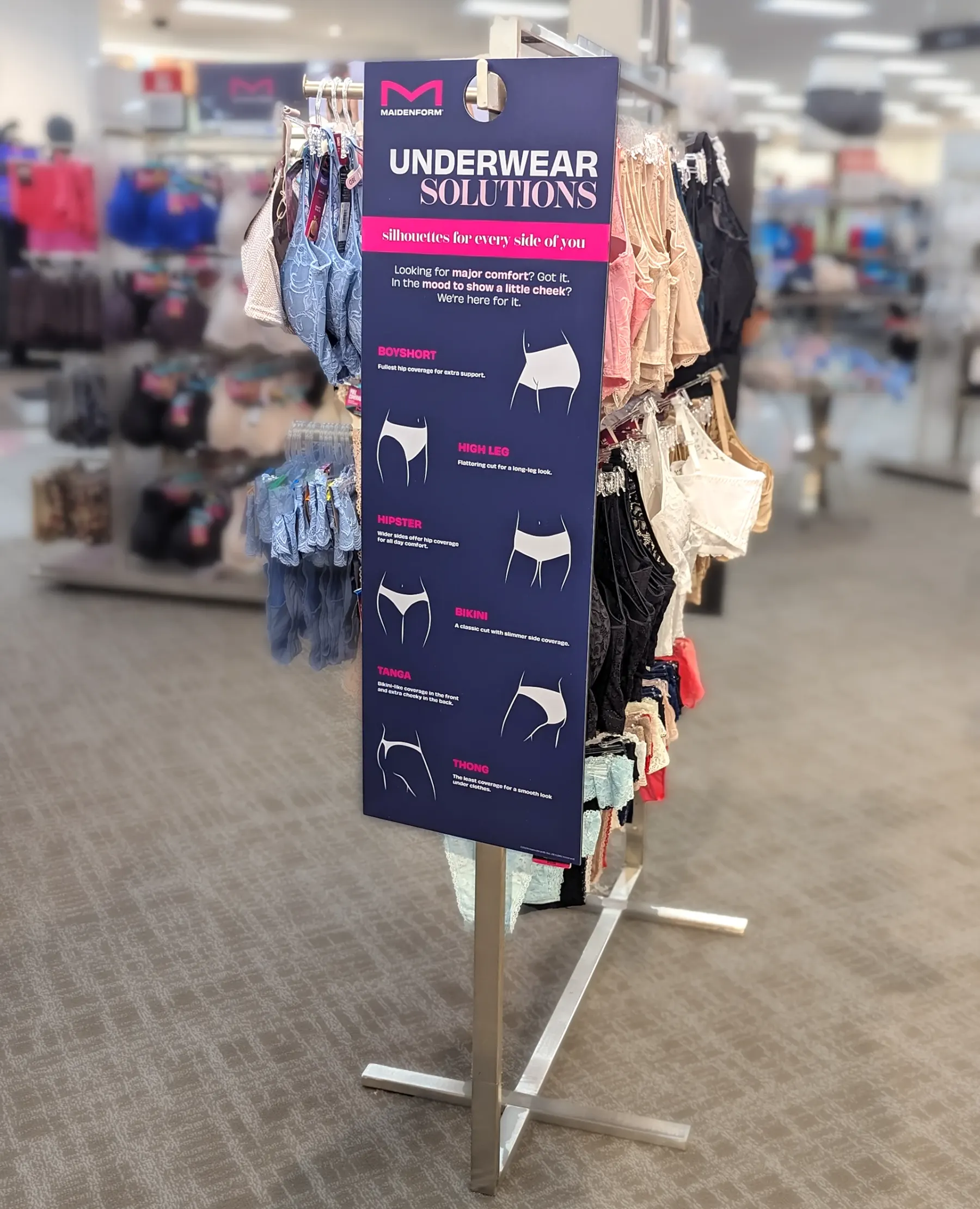 The Underwear Solutions panel on a steel floor stand in a department store, hanging rails of underwear either side of it.